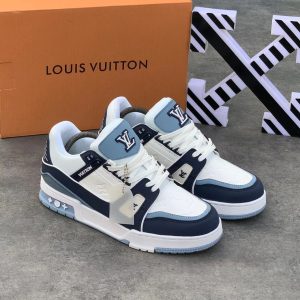 Sneakers in a light blue and white colorway, with a Louis Vuitton logo on the tongue and heel. The shoes are displayed on a gray surface with an orange Louis Vuitton shoebox in the background.